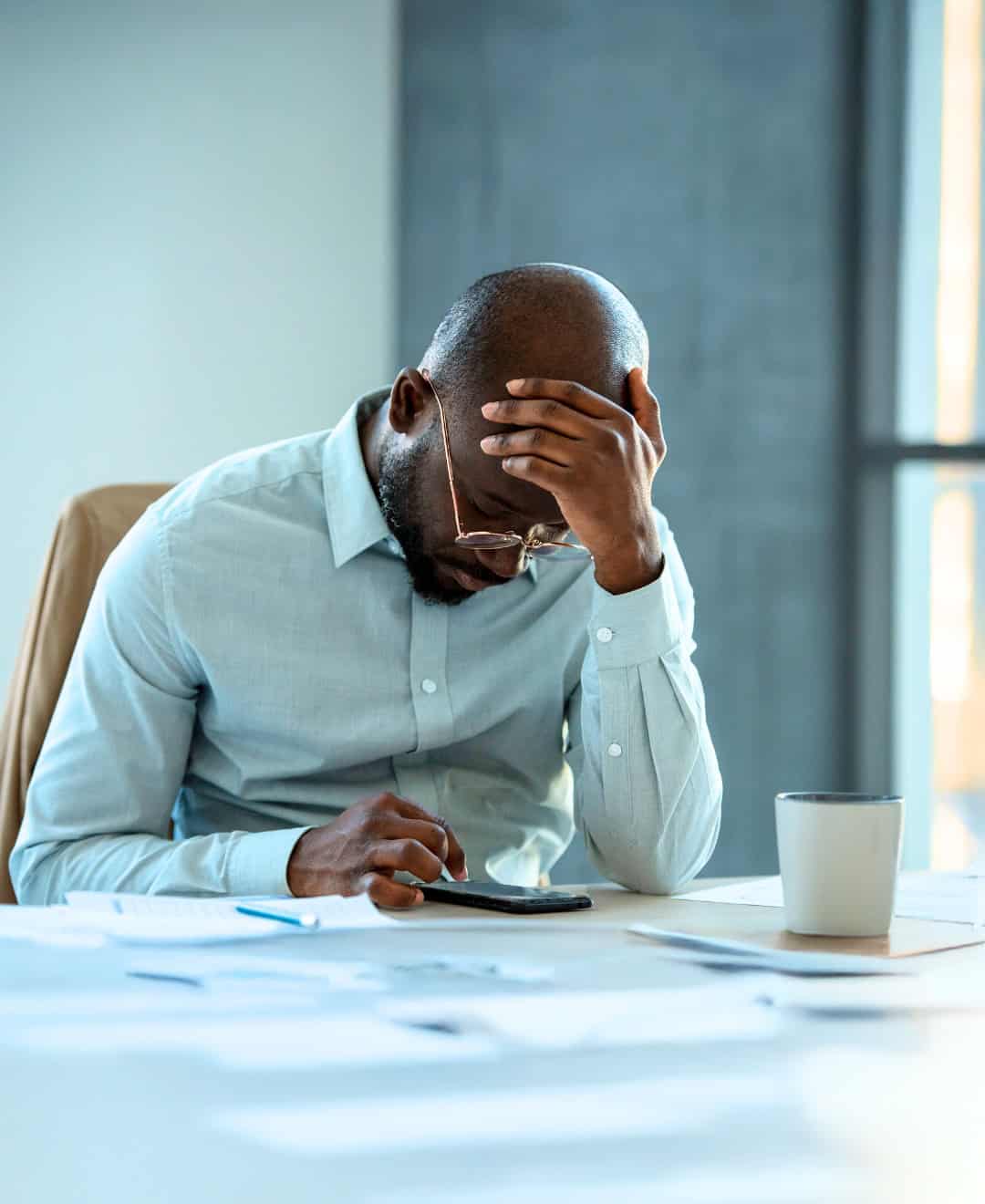 A man sitting at a desk with his head in his hands.